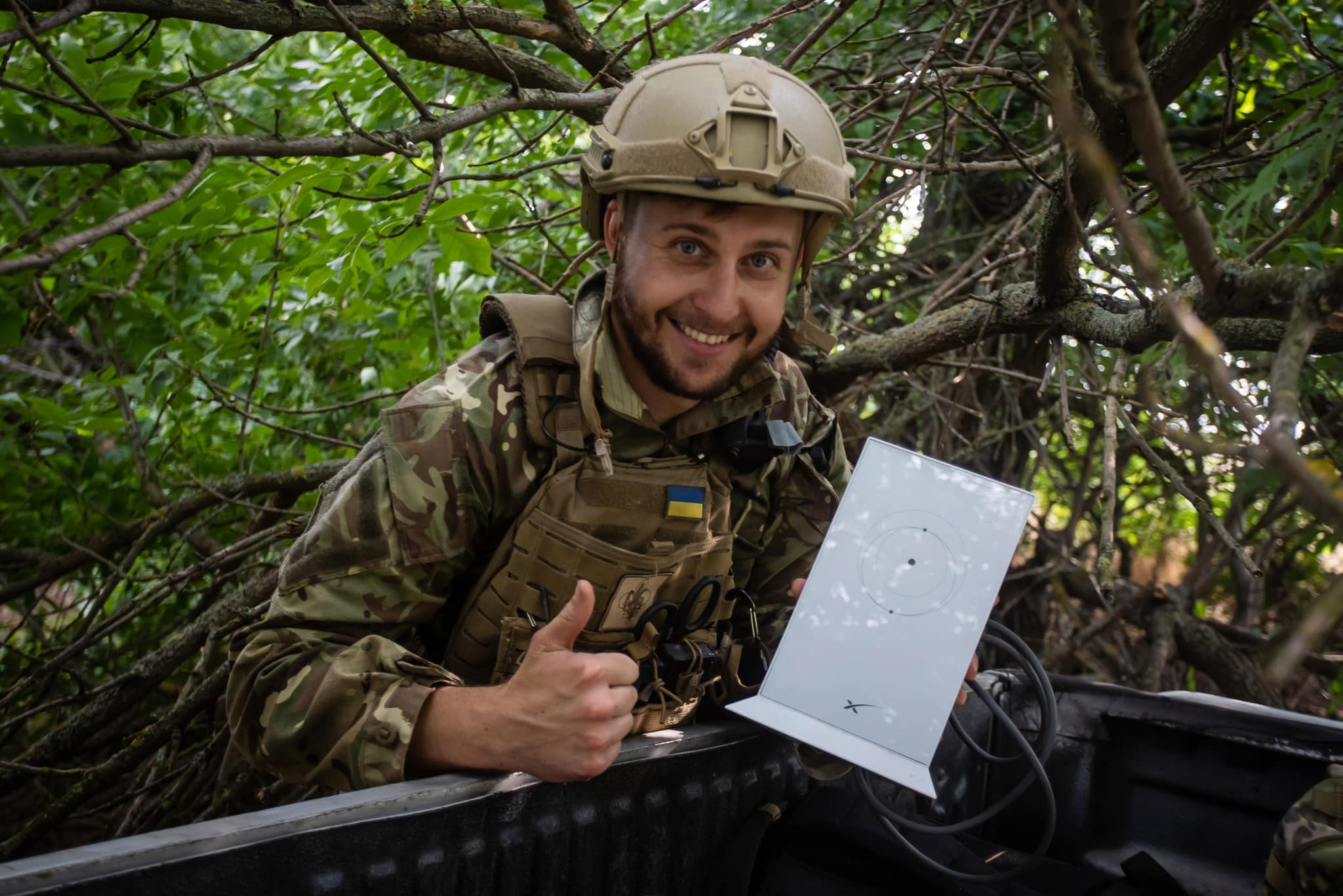 A picture of a Ukrainian soldier holding a Starlink router in a natural environment.